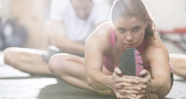 Portrait of confident woman doing stretching exercise in crossfit gym